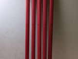 quatre battes de baseball en plastique rouge posées sur une table blanche