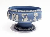 un vase bleu orné de motifs blancs, posé sur une surface blanche