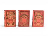 trois petits livres rouges sont alignés sur une surface blanche