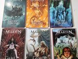 four books of the game of thrones series are on a table