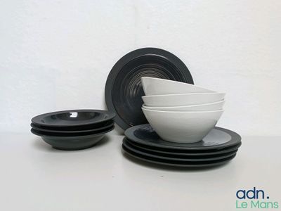 plusieurs bols et assiettes noirs et blancs posés sur une table blanche