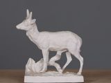 une statue blanche représentant un cerf, posée sur une table en bois