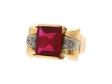 un gros plan d'une bague sertie d'une pierre rouge et de diamants
