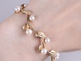 bracelet plaqué or orné de perles et de feuilles au poignet d'une femme