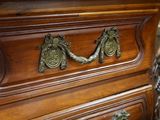 a wooden dresser with brass handles on top of it
