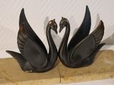 two black swans that are sitting on a wooden block