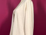 a white top on a mannequin stand against a red wall