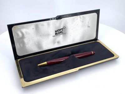 a red pen in a gold box on a white table