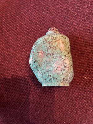 une photo d'une pierre verte posée sur un tissu rouge
