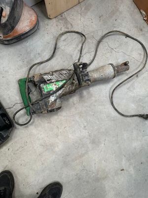 a broken drill on the floor next to a pair of shoes