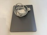 a white table with a laptop and a charger on it