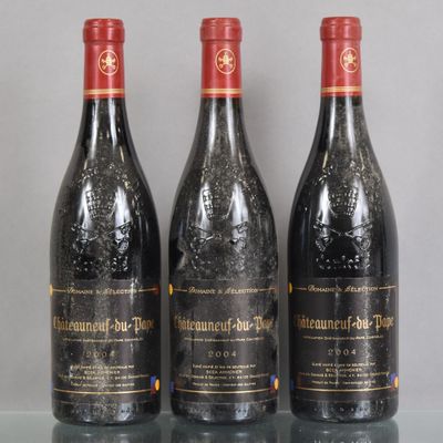 three bottles of wine sit on a glass table in front of a gray wall