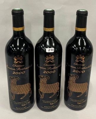 trois bouteilles de vin ornées de motifs dorés, posées sur une table