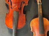three old violin ' s on a black surface with a black background