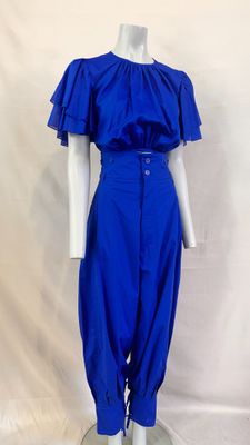 La robe est bleue et comporte des volants aux épaules.