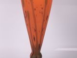 un vase en verre orange posé sur un socle noir