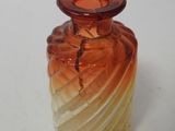 a small glass vase with a red top sitting on a table