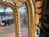a mirror that has a gold frame with pearls on it