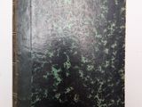 un vieux livre posé sur une table à côté d'un mur blanc