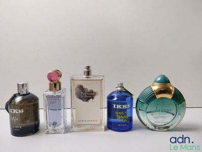 plusieurs types différents de flacons de parfum alignés sur une surface blanche