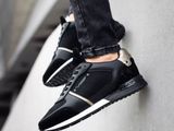 black and white sneakers with black and gold accents on a wall