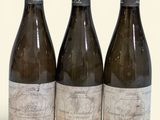 trois bouteilles de vin sont alignées sur une surface blanche