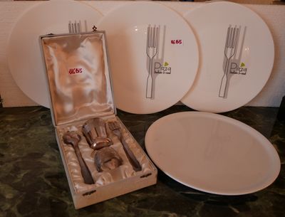 une boîte d'argenterie posée sur un plan de travail, à côté d'une assiette et d'une fourchette