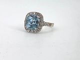 an image of a ring with a blue topaz stone surrounded by diamonds