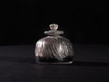 a small glass bottle with a silver lid sitting on a black surface
