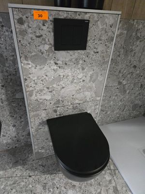 des toilettes noires situées dans une salle de bains, à côté d'une douche