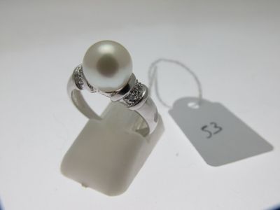 une bague ornée d'une perle blanche et d'une petite étiquette