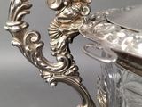 an antique silver plated bowl with a handle on a table