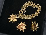 an image of a gold bracelet and star charms in a black box