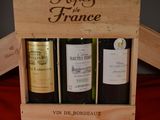 three bottles of wine in a wooden box on a table