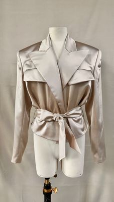 an image of a mannequin wearing a beige jacket with a bow tie