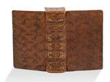 un vieux livre à la couverture brune posé sur une surface blanche