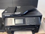 a black printer sitting on top of a wooden desk next to a window