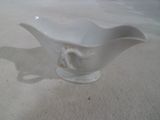 un petit bol blanc avec une anse posé sur une table