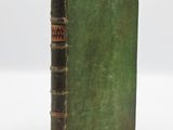 an old book with a green cover sitting on a white surface