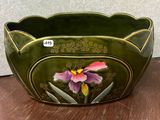 a green bowl with a flower on it on a table