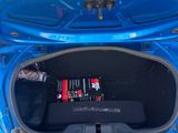 une voiture bleue avec tout un tas de batteries dans le coffre