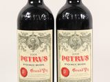two bottles of red wine sitting next to each other on a white surface
