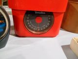 une horloge rouge posée sur une table à côté d'une plante en pot
