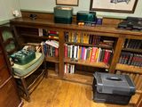 a wooden bookcase with many books and a suitcase on it