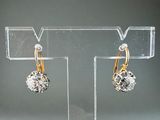 pair of gold and diamond earrings on display on clear acrylic stand