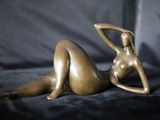 une statue en bronze représentant une femme allongée sur un canapé