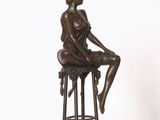 statue en bronze représentant une femme assise sur un tabouret, les jambes croisées