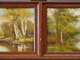 two paintings of trees and a river are hanging on a wall