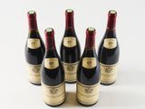 six bottles of wine are lined up in a row on a white surface
