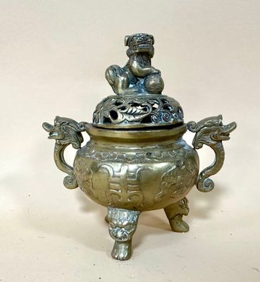 a small metal pot with a statue on it